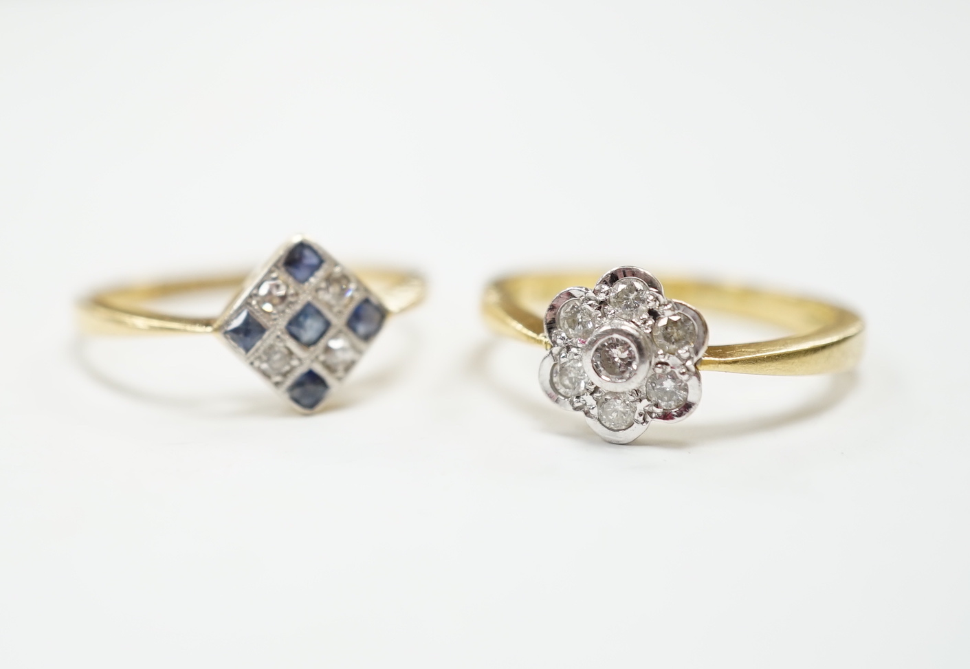 A 1920's 18ct, sapphire and diamond millegrain set cluster ring, size O/P, and a later 18ct gold and seven stone diamond set flower head cluster ring, gross weight 6.3 grams.
